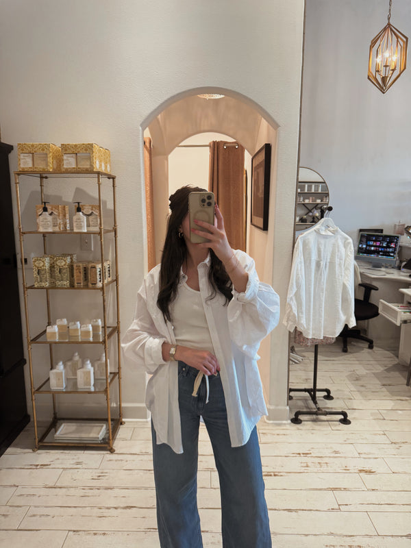 Boutique mirror photo of a woman wearing the Nella Pant with a light top.